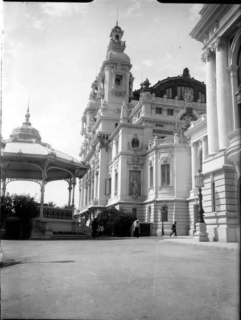 Здание казино Монте-Карло со стороны моря на старой чёрно-белой фотографии: башни, колонны и павильон слева